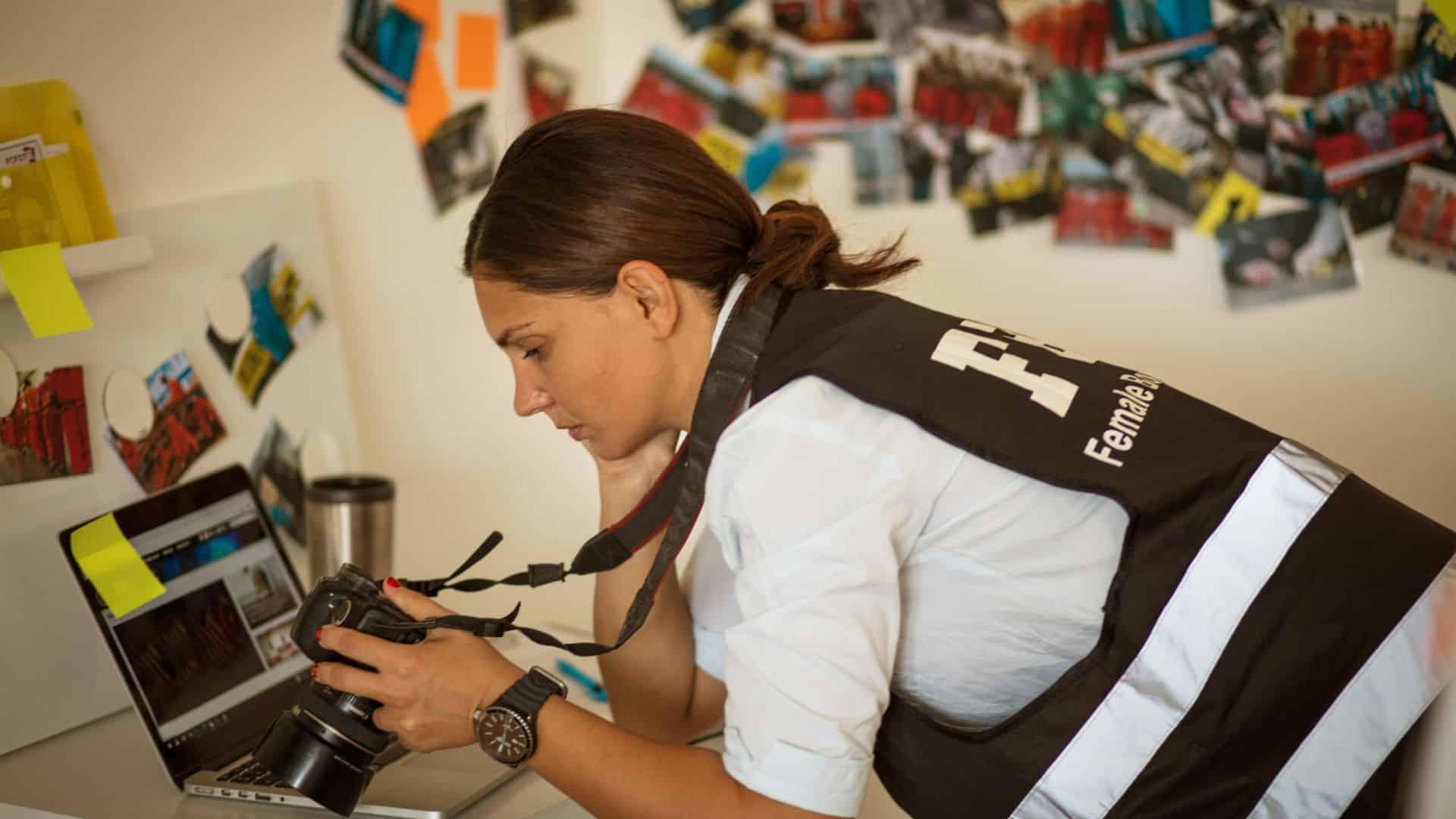 Frau beugt sich über einen Tisch und schaut in eine Kamera